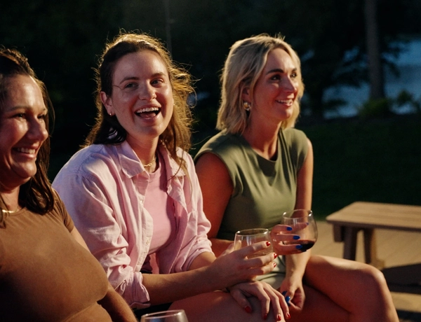 Group of women talking and laughing with drinks by the fire pit