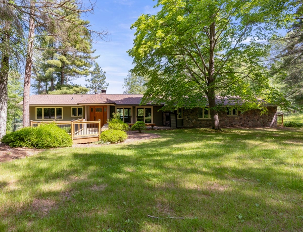 The exterior of Birchview cottage with an orange front door, sliding glass doors, a wooden bench, and fenced walkway leading to the building