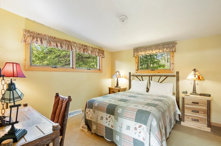 A bedroom at Garden cottage with one bed covered by a quilted bedspread and a desk