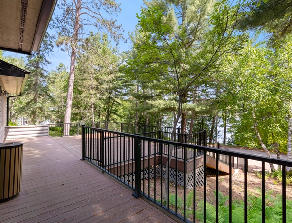 Hilltop cottage deck looking out into the trees with the lake just past the tree-line