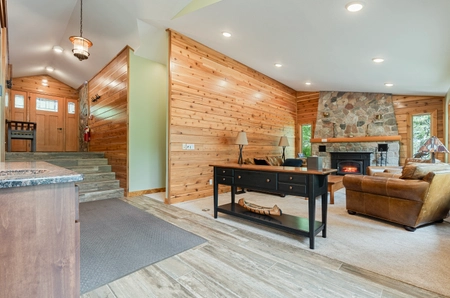 Living room of hilltop cottage with a fireplace, console table, and a combination of wood and green walls