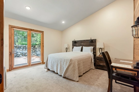 Bedroom at hilltop cottage with sliding glass doors and a single bed with a tan bedspread