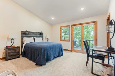 Bedroom at hilltop cottage with a single bed covered by a blue comforter and sliding glass doors leading to a balcony