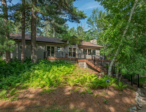 Exterior of a cottage with a big deck surrounded by trees