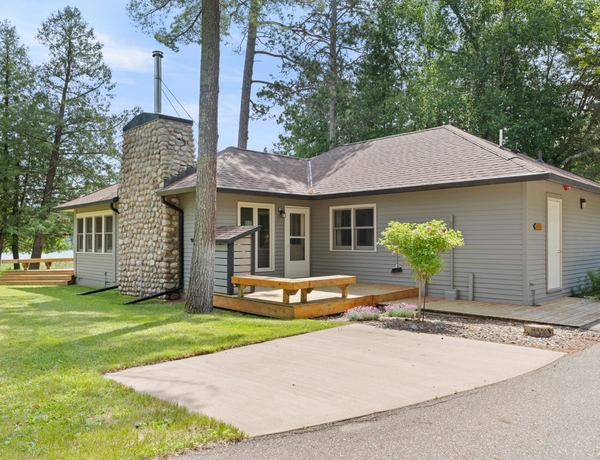 The exterior of petite cottage with a small front porch and a stone chimney