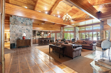The living room of Pineview cottage with large floor-to-ceiling windows, chairs and couches, and stone accent walls