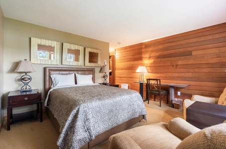 A bedroom at Pineview cottage with a single bed, two chairs, a desk, and two nightstands