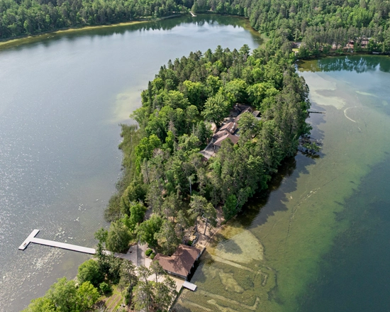 Aerial view of an inlet with water on either side - several cottages can be seen peeking out of the dense trees