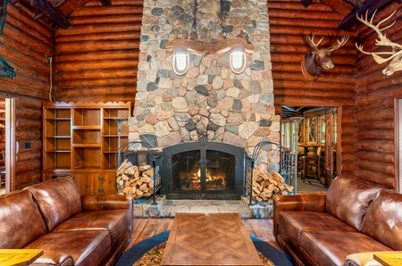 Fire place of the main lodge with a stone chimney near two brown leather couches