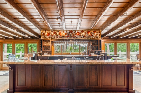 A bar area below a long golden light fixture with red accents and warm lighting