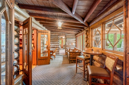 Small foyer with several chairs and tables underneath paneled windows