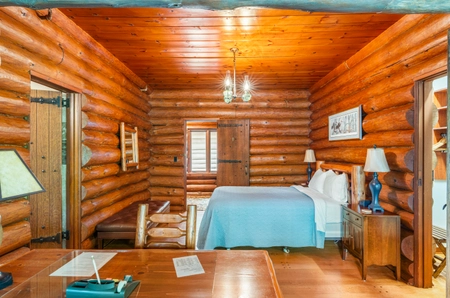 Main lodge bedroom with a single bed covered by a blue bedspread, a desk, and a nightstand