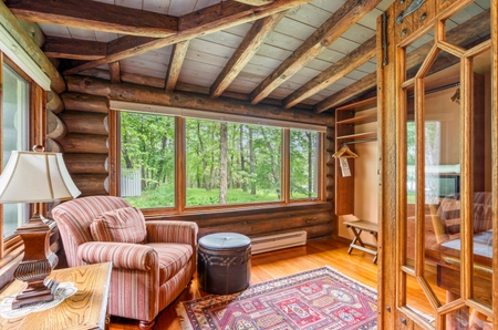 A foyer in the main lodge with a wide window, red-striped chair, and ottoman